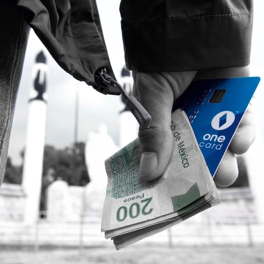 Hand holding a blue One Card alongside Mexican currency, selective colour treatment